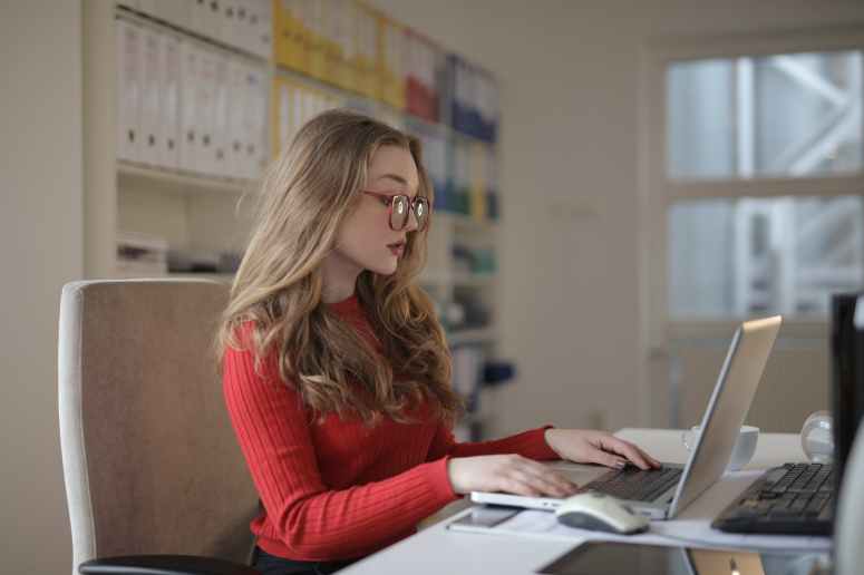 woman in red long sleeve shirt wearing eyeglasses using macbook air